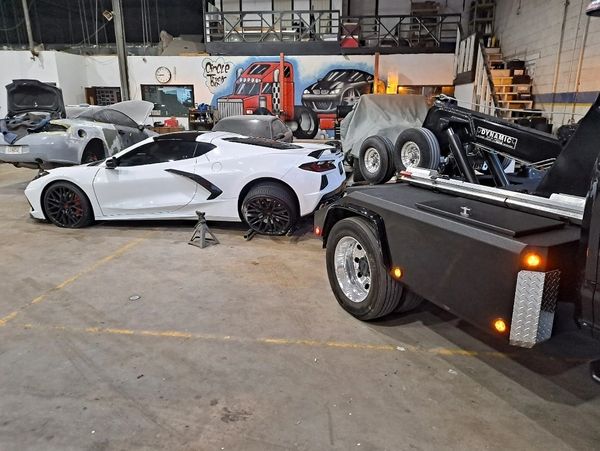 White car being loaded onto a flatbed tow truck.