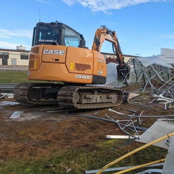 excavator in front of demolished building