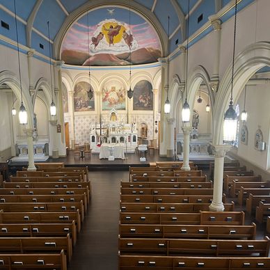 Interior view of a grand church with wooden pews and religious murals.