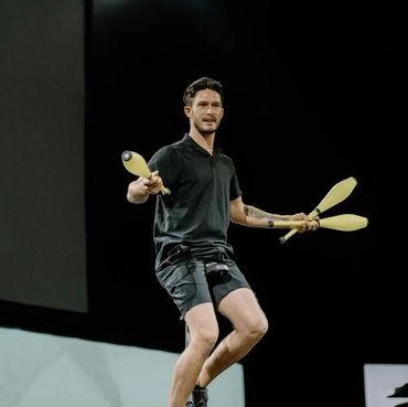 A man juggling clubs under the moonlight.