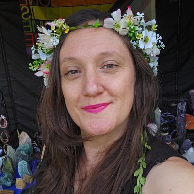 Woman with flower crown and pink lipstick smiling.