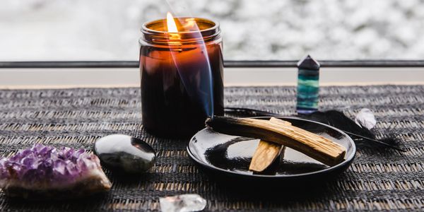 A display of spiritual tools including crystals, candles and cleansing palo santo wood.