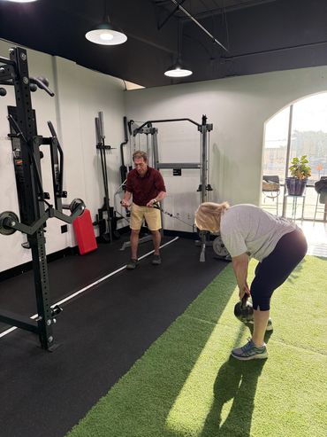 Two people exercising in a gym with weights and machines.