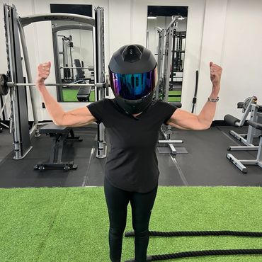 Person in a helmet flexes muscles inside a gym.