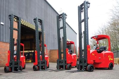 Four red forklifts parked outside a warehouse building.