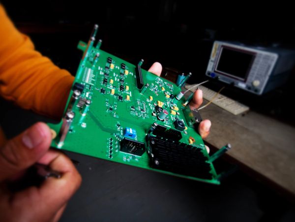 Hand holding a green circuit board.