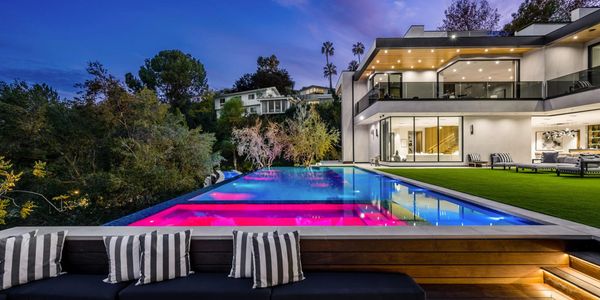 Modern house with an illuminated infinity pool at dusk.