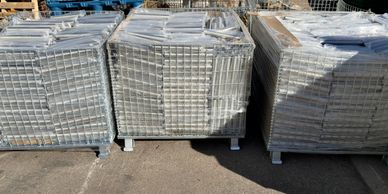 Three pallets stacked with metal grids wrapped in plastic.
