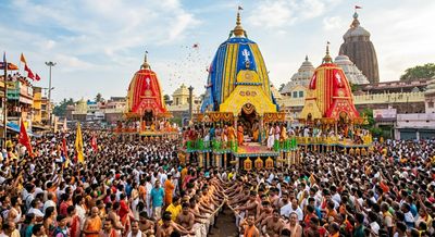 Large crowd participating in a vibrant Indian chariot festival with decorated chariots.