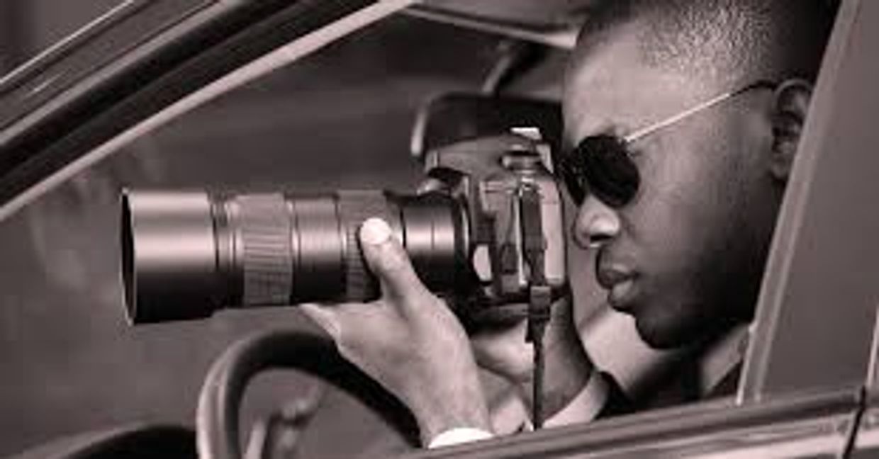 Man using a camera with a long lens from a car.