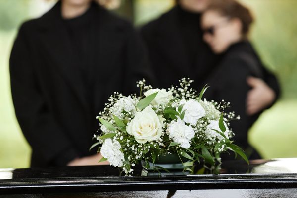 White funeral flower bouquet on top of a closed coffin.