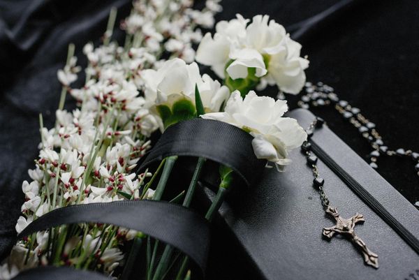 White funeral bouquet beautifully wrapped with black silk.