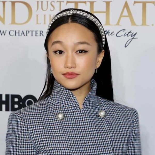 Woman with jeweled headband and patterned jacket at an event.