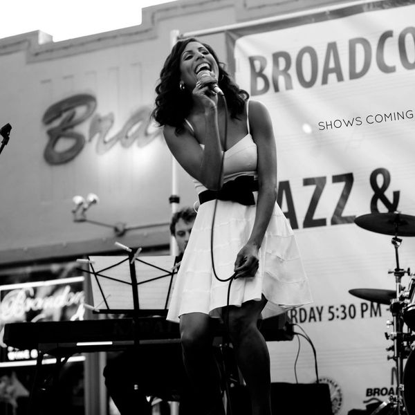 Woman singing passionately on stage with a microphone.