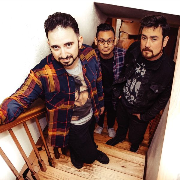 Three men posing on a wooden staircase.