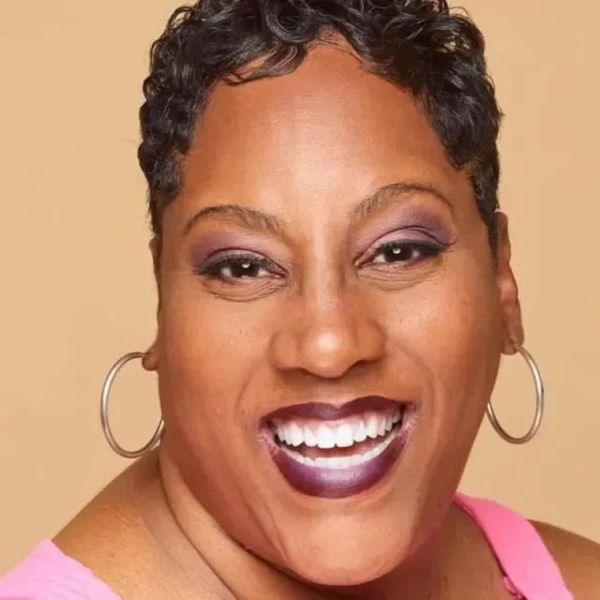 Close-up of a smiling woman with short hair and hoop earrings.