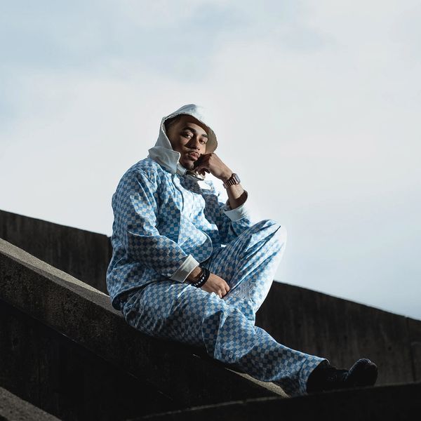 Man in patterned blue outfit sitting on outdoor steps.