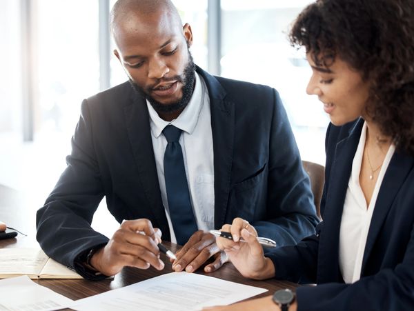 Two professionals review documents together at a table.