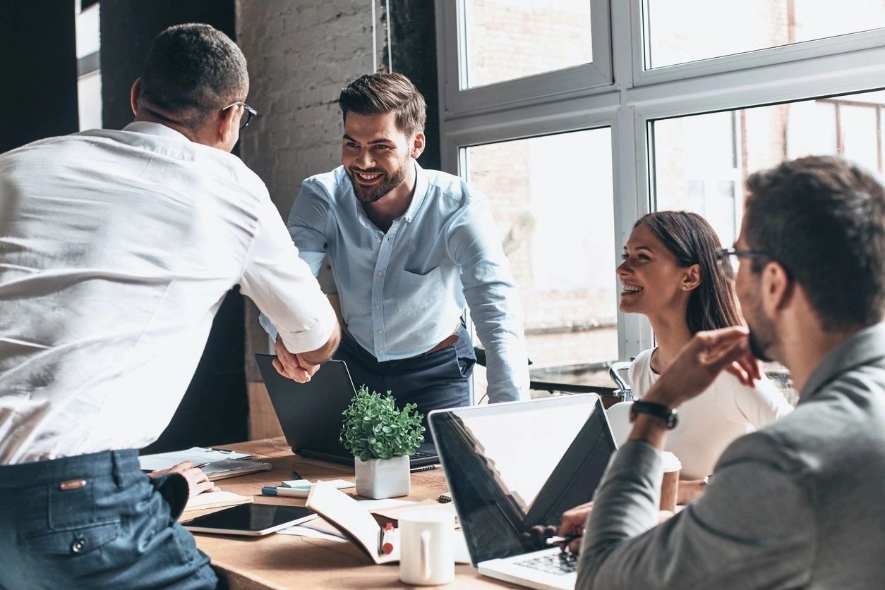 Business professionals shaking hands in a modern office meeting.