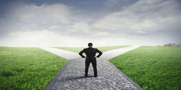 A man stands at a fork in the road, contemplating which path to take.
