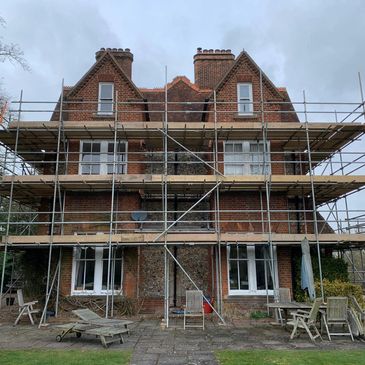 Brick house under renovation with scaffolding.