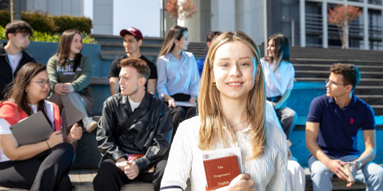 Young woman smiling with a group of students outdoors.