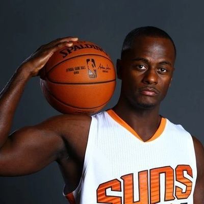 Basketball player in Suns jersey holding a basketball on his shoulder.