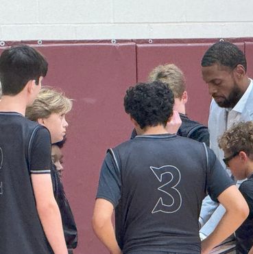 Coach discussing strategy with young basketball players during a timeout.