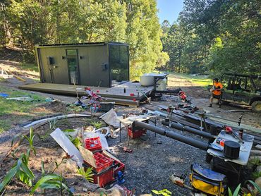 Construction site with a modern tiny house in a forested area.