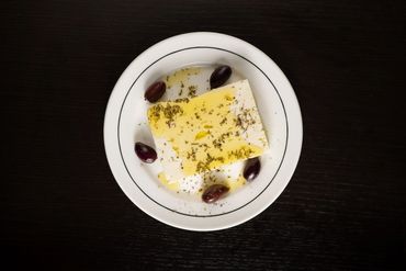 Plate with feta cheese, olives, and olive oil drizzle.