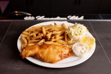 Plate of fish and chips with coleslaw, tartar sauce, and lemon wedge.
