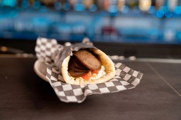 A gyro pita wrapped in checkered paper on a plate.