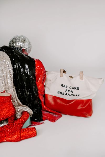 Silver, Black and Red sequin jackets, silver disco ball, and red sequin boots with bag that says Eat