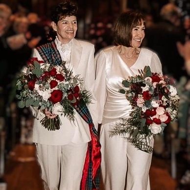 Brides wearing an ivory suit and an ivory silk jumpsuit