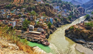 A town built on hillsides beside converging rivers in a mountainous region.