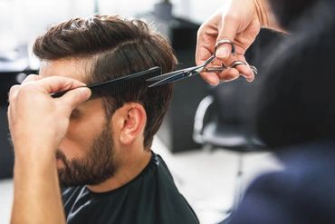A man getting a haircut with scissors and a comb.