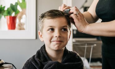 A young boy getting his hair cut at home with a smile.