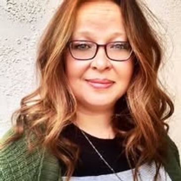 Smiling woman with glasses and wavy hair.