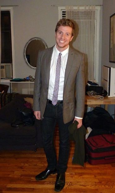 man in suit and checkered tie posing in front of table