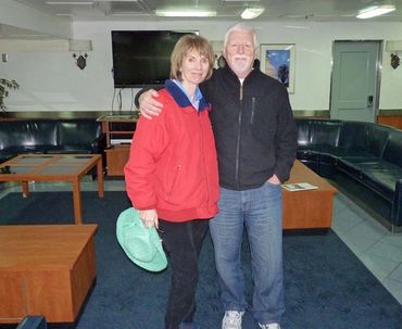 grandparents posing for photo with black leather couch