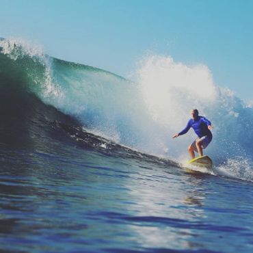 grandfather surfing on wave wearing blue