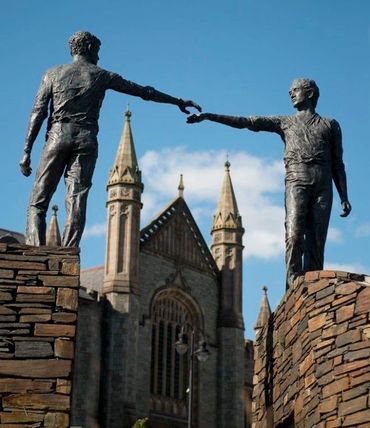 statues of two people reaching out for each other
