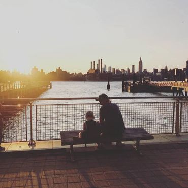 child with parent sitting on stone bench in front of lake