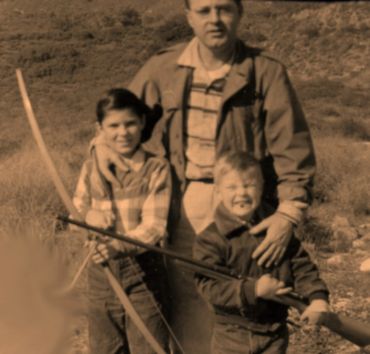 sepia-toned photo of father and children with bow and gun