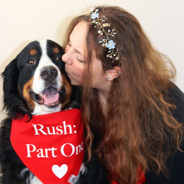 Bridget L. Rose kisses the top of a Bernese Mountain Dog wearing a bandana with "Rush: Part One"