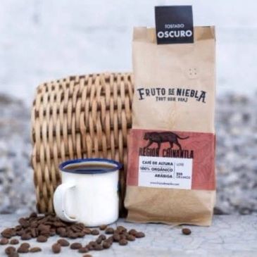 Bolsa de café y taza sobre mesa con granos.