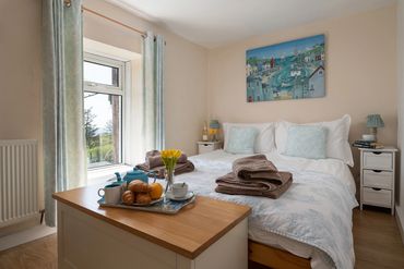 KS bed with white organic linen, showing view from the window on a sunny day. Flowers on tea tray