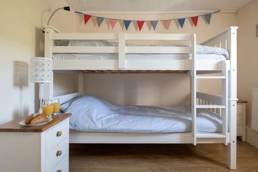 The children's bunks at this self catering cottage made up with blue organic bedlinen and bunting