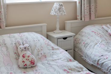 Twin room at Arallt Holiday Cottage, made up for two young guests with white furniture