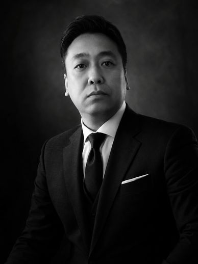 Black and white portrait of a serious man in a suit and tie.